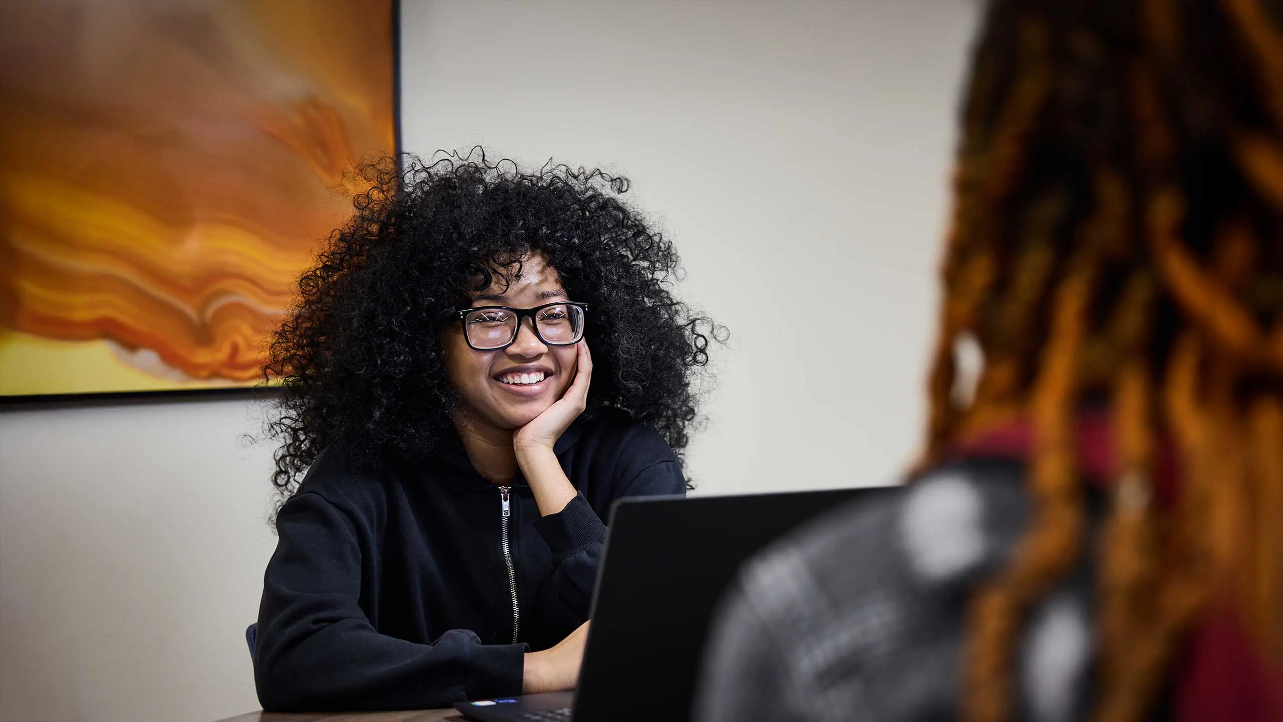Student smiling while behind laptop